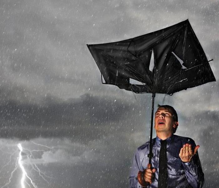 a picture of a man with a broken umbrella in a lightning storm